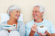 Senior couple sitting on bed in the morning
