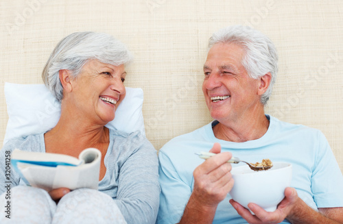 Photo: Senior couple sitting on bed in the morning Senior couple sitting on bed in the morning