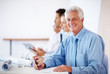 Happy mature businessman writing notes during meeting