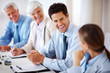 Smiling businessman sitting in meeting with colleagues