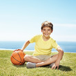 Photo: Portrait of cute little boy sitting on grass with a basketball Portrait of cute little boy sitting on grass with a basketball