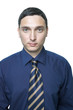 Serious young man in dark blue shirt and tie isolated on white