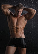 Wet muscle sexy young man posing under the rain in studio