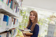 girl choosing book in library and smiling