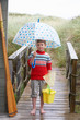 Boy standing on footbridge with umbrella