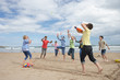 Teenagers playing baseball on beach