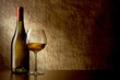bottle with white wine and glass on a old stone. glass in the fo