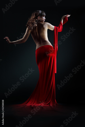 Photo: The girl in a red dress against a dark background The girl in a red dress against a dark background