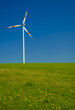 windrad steht auf einer wiese vor blauem himmel
