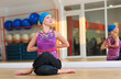 Young woman doing yoga on the floor of gym