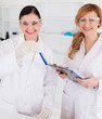 Two scientists looking at the camera while holding a test tube a