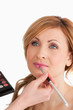 Young blond-haired female having her make up done by a make up a
