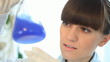 Female scientist examines Erlenmeyer flask, zoom in