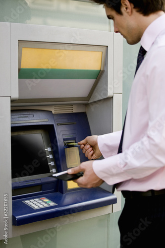 Photo: A businessman using a cash machine A businessman using a cash machine