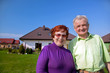 Senior smiling couple in front of their house