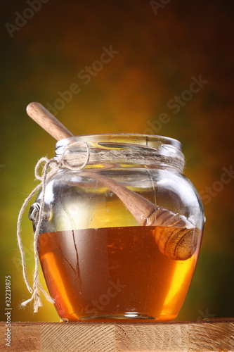 Photo: Pot of honey and wooden stick in it Pot of honey and wooden stick in it