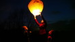 woman holds chinese lantern, children look, then she releases