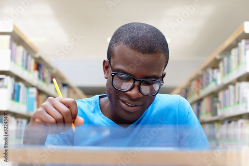 Photo: young african man studying in library young african man studying in library