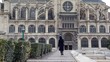 woman goes on square to ancient cathedral from camera