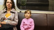 mother with her little daughter sit in riding subway train