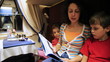mother reads book to son and daughter sitting in train