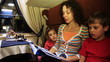 mother reads book to son and daughter sitting in riding train