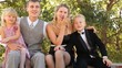 Family in celebratory clothes sits on bench in summer day