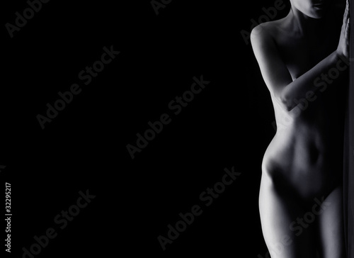 Photo: Beautiful naked body of a young woman on a black background Beautiful naked body of a young woman on a black background