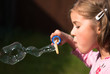 Beautiful little girl blowing a magical soap bubble