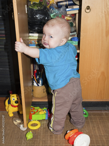 wallpaper baby boy10. The aby opened the cupboard and looks at the backside. Boy 10 m