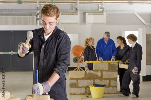 Foto: Student hammering chisel on brick in vocational school Student hammering chisel on brick in vocational school