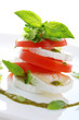 Fresh salad with goat cheese, tomato and basil pesto on a white Fresh salad with goat cheese, tomato and basil pesto on a white