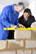Foto: Teacher talking to student using level in bricklaying vocational school Teacher talking to student using level in bricklaying vocational school
