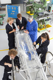 Photo: Teacher helping students constructing electric vehicle prototype in vocational school Teacher helping students constructing electric vehicle prototype in vocational school