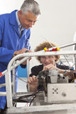 Photo: Teacher helping student constructing electric vehicle prototype in vocational school Teacher helping student constructing electric vehicle prototype in vocational school