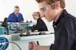Teacher talking to students using lathe in vocational school