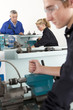 Teacher talking to students using lathe in vocational school