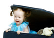 Baby looks from a travel bag suitcase with toys Baby looks from a travel bag suitcase with toys