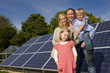 Smiling family standing together near large solar panels