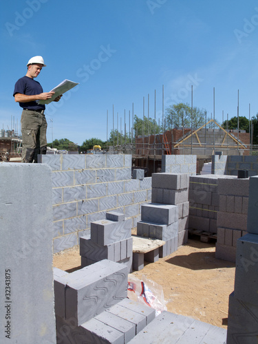 Photo: Construction worker holding blueprints on construction site Construction worker holding blueprints on construction site