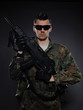 Foto: Young soldier in camouflage and ammunition with a gun. studio sh Young soldier in camouflage and ammunition with a gun. studio sh