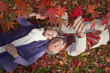 Photo: Smiling senior couple laying on ground underneath red autumn leaves Smiling senior couple laying on ground underneath red autumn leaves