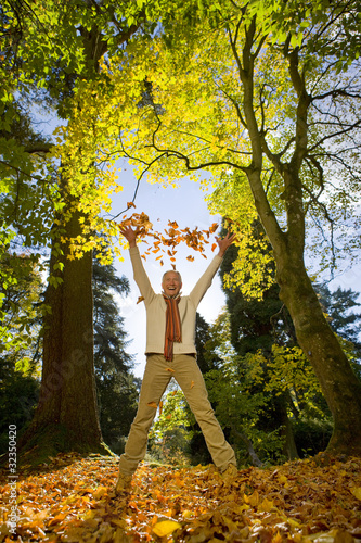 Photo: Laughing senior man throwing autumn leaves in air Laughing senior man throwing autumn leaves in air