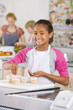 Smiling student putting sprinkles on cupcakes in home economics class