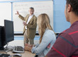 Teacher at whiteboard explaining lesson to students in classroom
