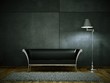 Schwarzes Ledersofa vor Betonwand