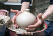 The hands of a potter, creating an earthen jar on the circle