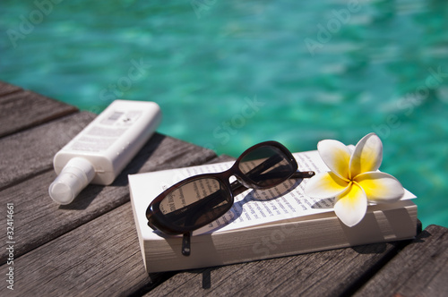 Photo: Livre, lunettes et crème solaire à la piscine Livre, lunettes et crème solaire à la piscine