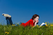 Girl reading book lying on green meadow Girl reading book lying on green meadow