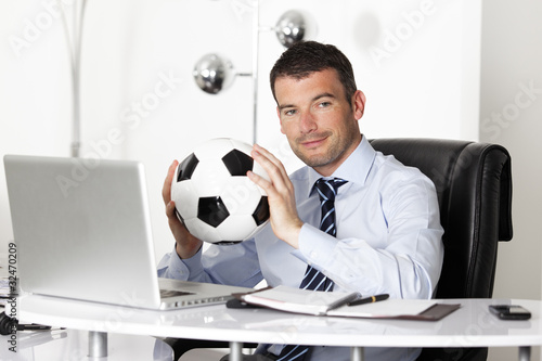 Photo: young businessman in office with computer and ball young businessman in office with computer and ball
